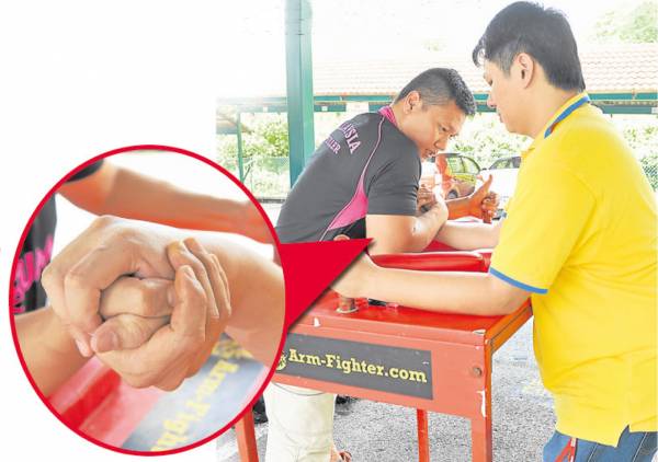 萧汉铭与记者一起示范腕力摔角动作,他强调除了握紧对方的手,肚子更要贴着桌子(擂台),力气才能瞬间爆发击倒对手。
