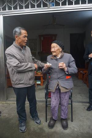 江十一嫂是长寿村里最年长的一位,如今104岁的她已四代同堂,但仍可以到邻居家串门子,左为其幼子江富山。