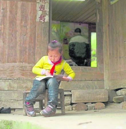 放学回家,欣欣在家门口看漫画。除了做力所能及的家务活,在山里,这是他们的娱乐。