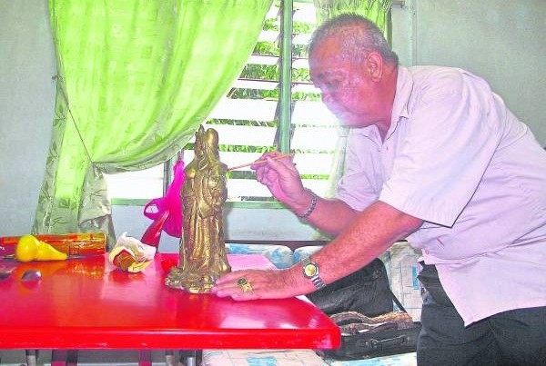 吴俊融师父重新为旧神像上金漆。