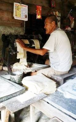 廖炳鸿老练的手法操作着手摇式的搅面机。