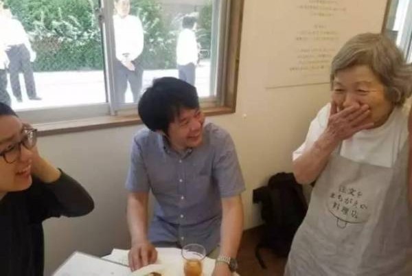 老人服务员发现上错菜,不好意思地笑了。