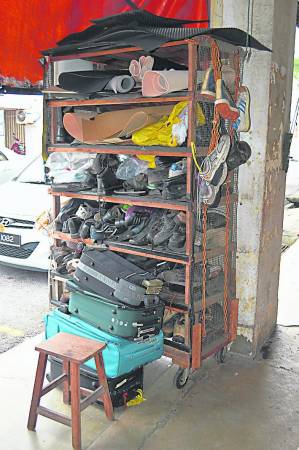 “张鞋店”门口摆设一个简陋的自制木架收纳柜，堆满已修补好的皮鞋。