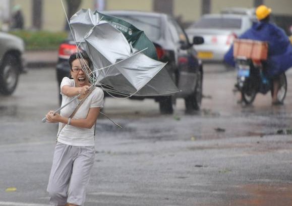 台风“海燕”袭击琼海市街头,一名行人的雨伞瞬间遭强风折断。