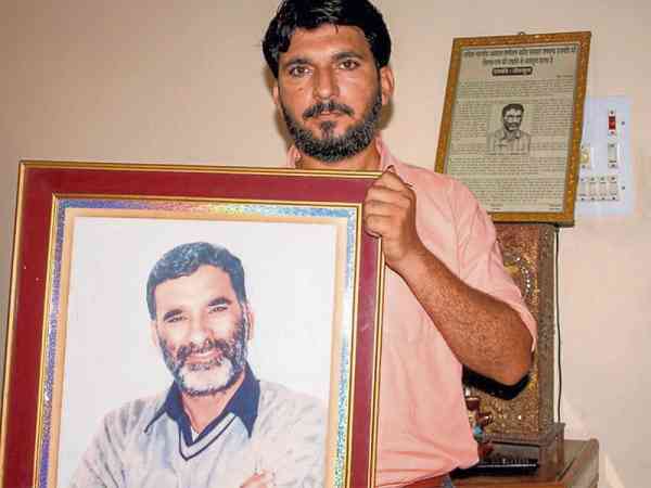 贾特拉帕蒂的儿子，展示亡父的遗照。这名印度新闻编辑所属的报刊曾指控古密星涉嫌强暴，之后他就被人枪杀。