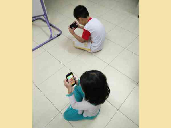 孩子低头玩手机，不但伤眼，更伤脊椎，影响发育。