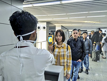 In this handout photograph taken and released by the Ministry of Civil Aviation (MoCA) on January 21, 2020, a man (L) uses a thermographic camera to screen the head of people at Netaji Subhash Chandra Bose International Airport in Kolkata, following the Ministry of Health and Family Welfare's advisory to screen passengers arriving in India from China and Hong Kong regarding the novel coronavirus (nCoV) issue. - Asian countries on January 21 ramped up measures to block the spread of a new virus as the death toll in China rose to six and the number of cases jumped to almost 300, raising concerns in the middle of a major holiday travel rush. (Photo by Handout / Ministry of Civil Aviation (MoCA) / AFP) / RESTRICTED TO EDITORIAL USE - MANDATORY CREDIT "AFP PHOTO / Ministry of Civil Aviation (MoCA)" - NO MARKETING - NO ADVERTISING CAMPAIGNS - DISTRIBUTED AS A SERVICE TO CLIENTS