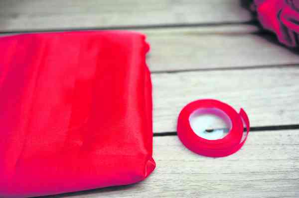 材料：红布、红色缎带、剪刀。（可自己拿捏尺寸，并使用不同颜色的布，以制作出不同大小的彩球。）