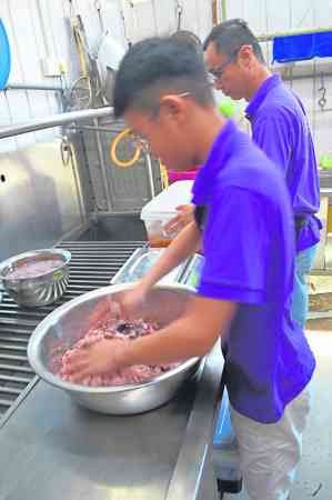 制作过程1:李宝发将调制好绞肉交由儿子搓匀。