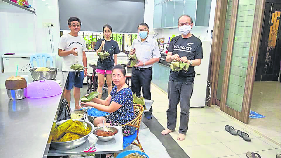 粽叶、糯米和棉线经过志愿者们的巧手,瞬间变成了有棱有角的粽子。