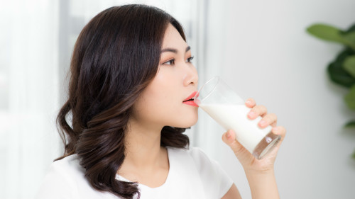 Beautiful asian girl drinking a glass of milk.