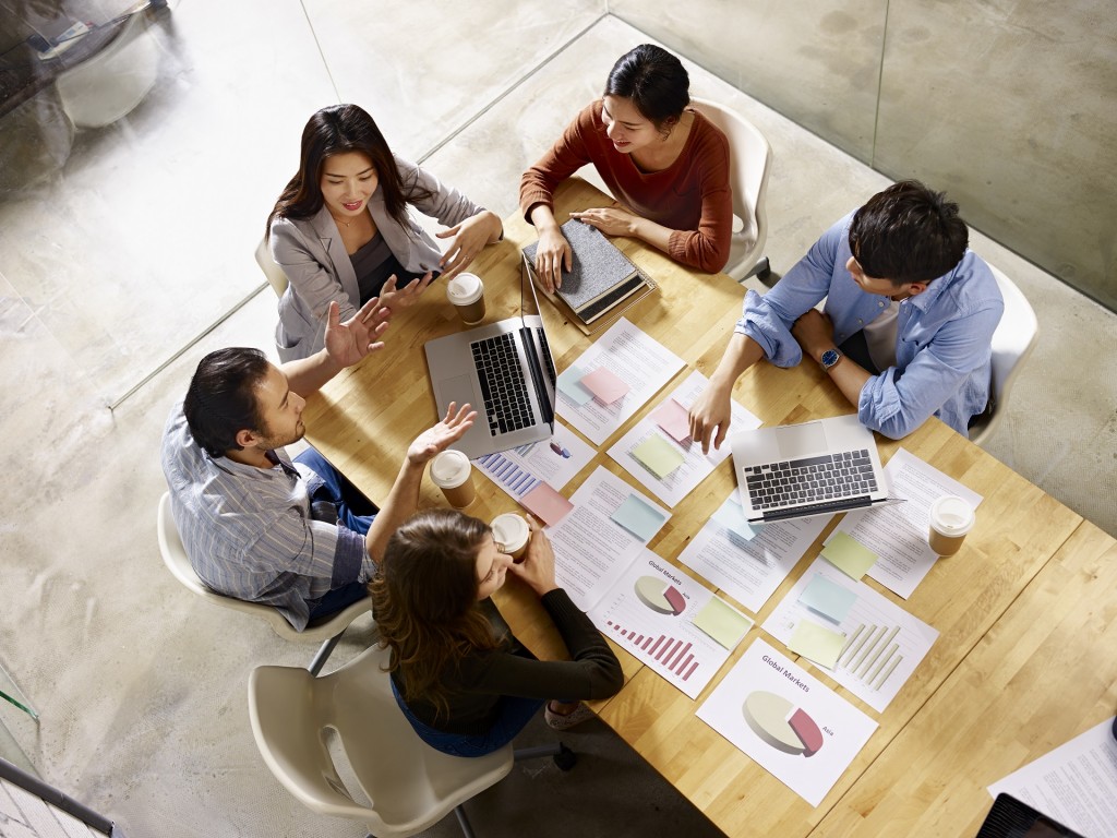 high angle view of a team of asian and caucasian corporate executives discussing business in meeting room.