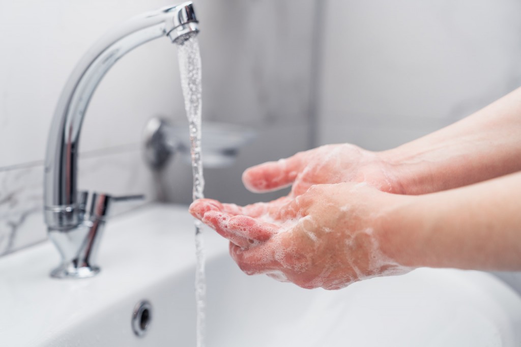 woman cleaning her hands with soap on faucet to protect from virus