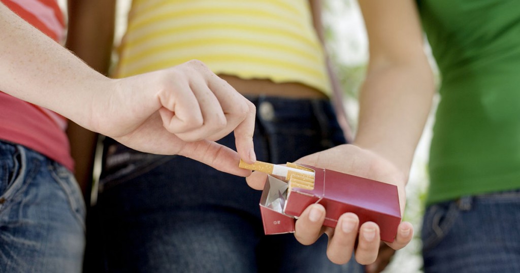 Teenage girl taking cigarette from friend cigarette pack, close-up