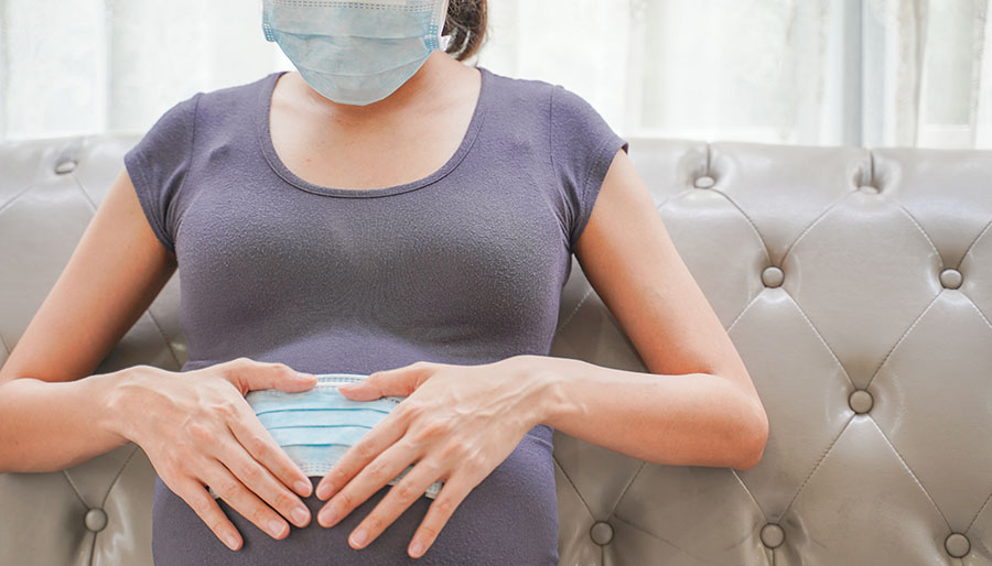 A pregnant woman wears a surgical mask to protect a COVID-19 (Co