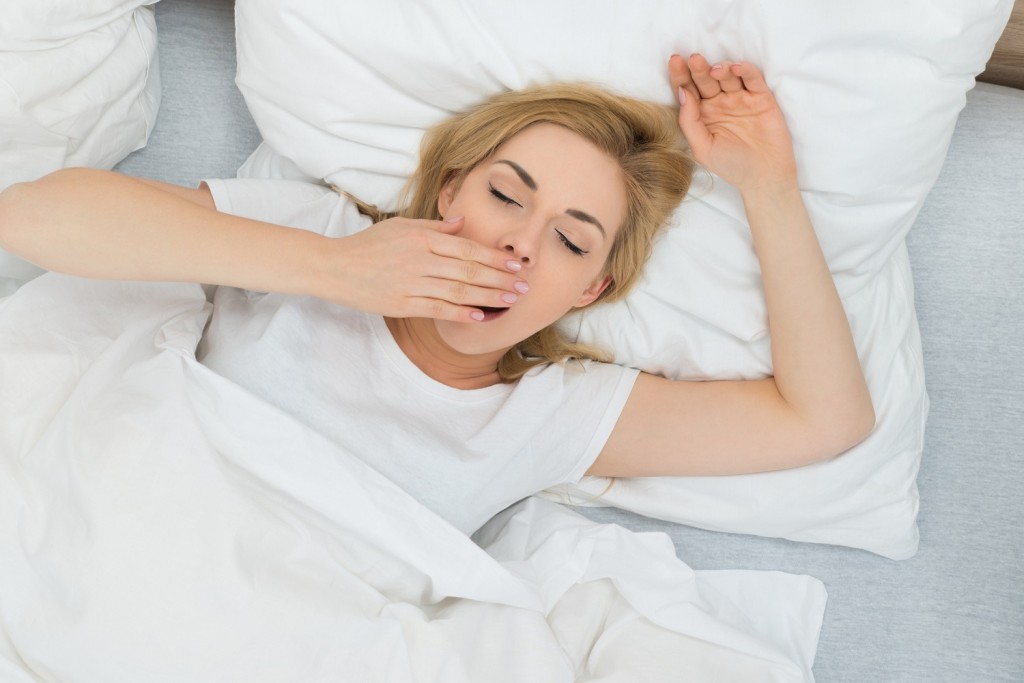 Young Woman Yawning In Bed At Home