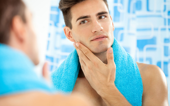 Young handsome man touching his smooth face after shaving