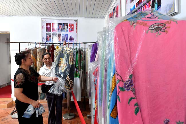 欧成斌(右)与徒弟谢金钗正在挑选服装准备排练。