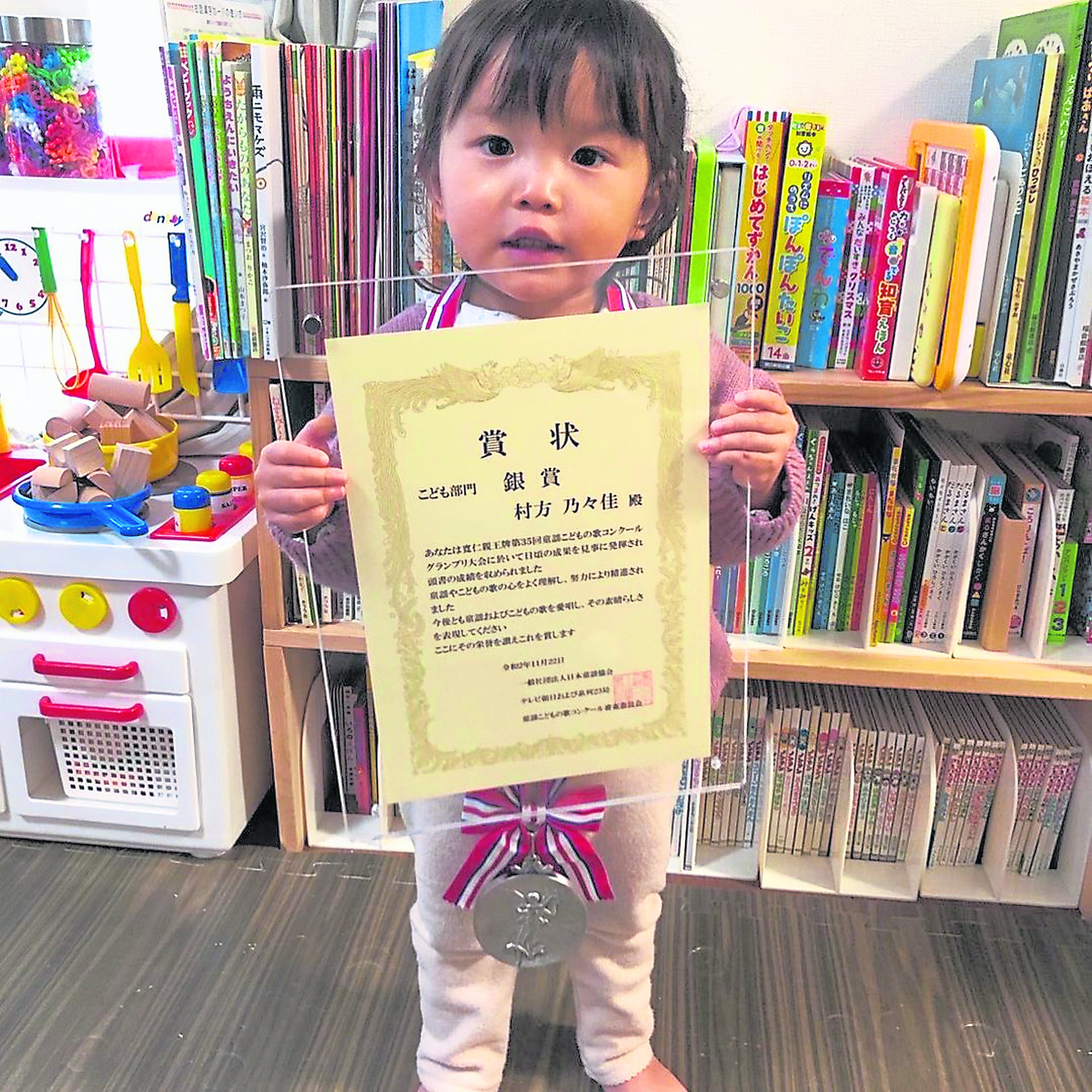在2岁5个月大时因为《小狗警察》的精彩演出，村方乃乃佳获得了这届日本童谣大赛的银奖，但是人气却盖过了其他所有同场表演的孩子。