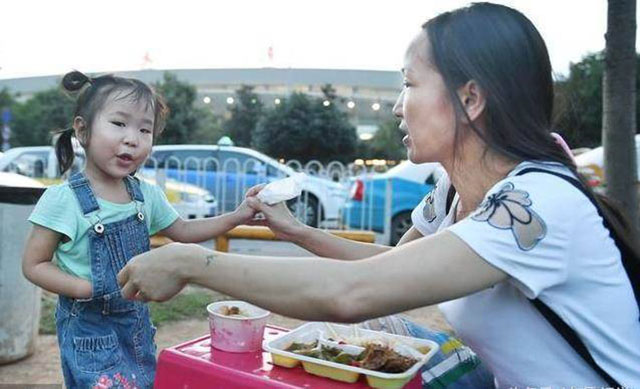 为在天河机场候客时，母女俩在路边买饭充饥。