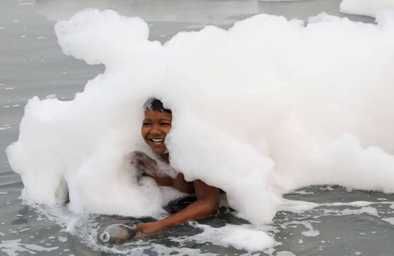印度恒河支流亚穆纳河出现白色泡泡状的污染物，仍有孩童在河边嬉戏。