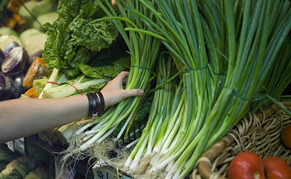 Person grabbing for bundle of green onions