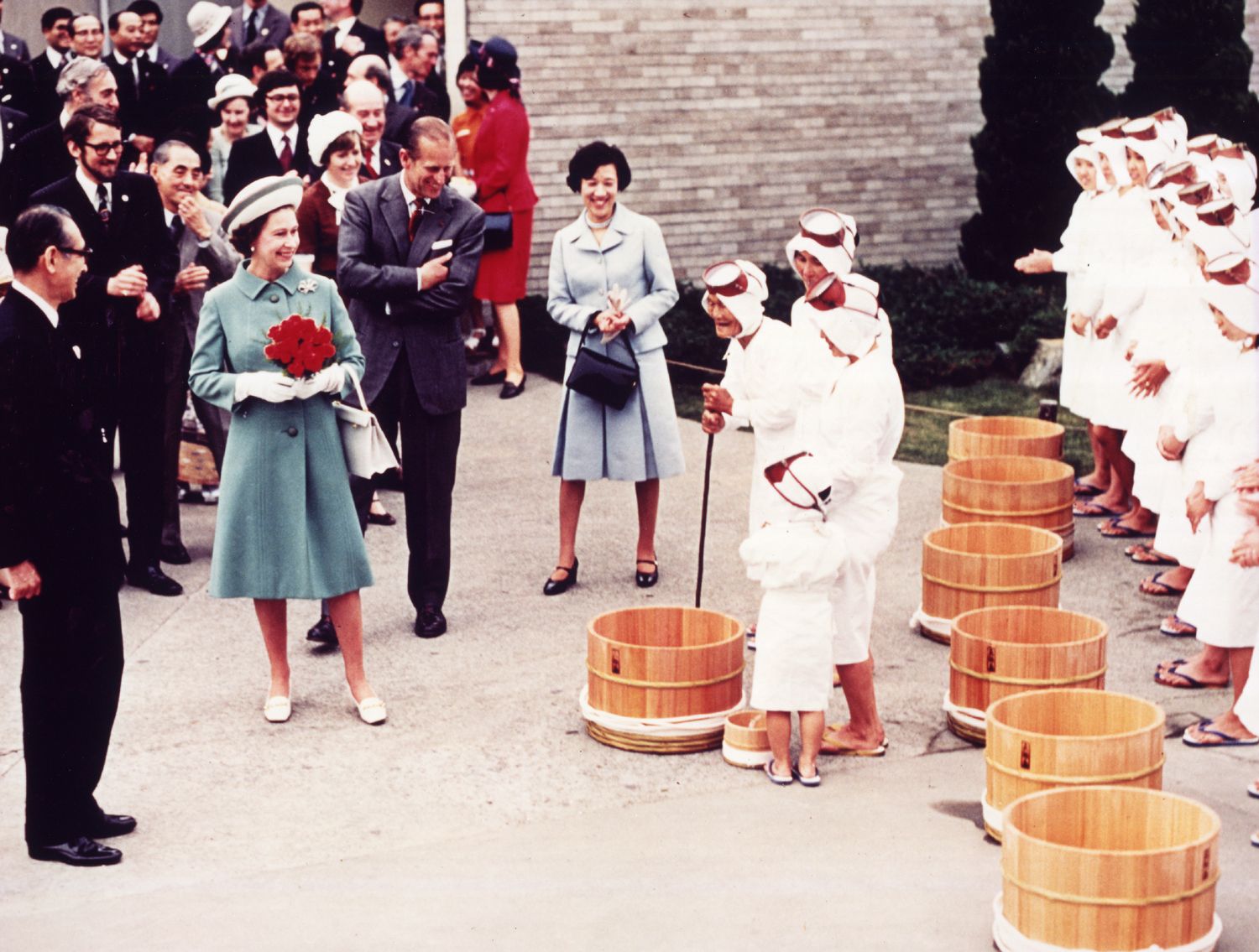 伊丽莎白二世（捧花者）与夫婿菲利普亲王，于1975年造访日本珠宝品牌MIKIMOTO为于三重县的珍珠岛。