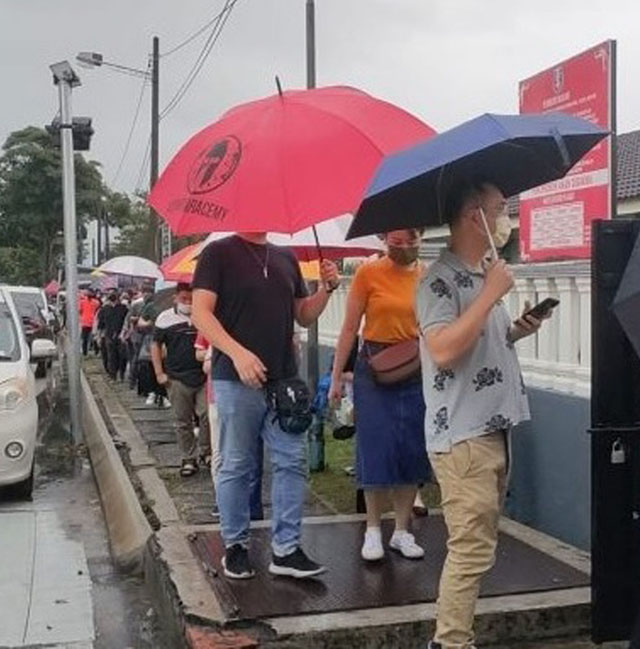 选民无惧雨天,撑伞冒雨到投票中心履行公民责任。