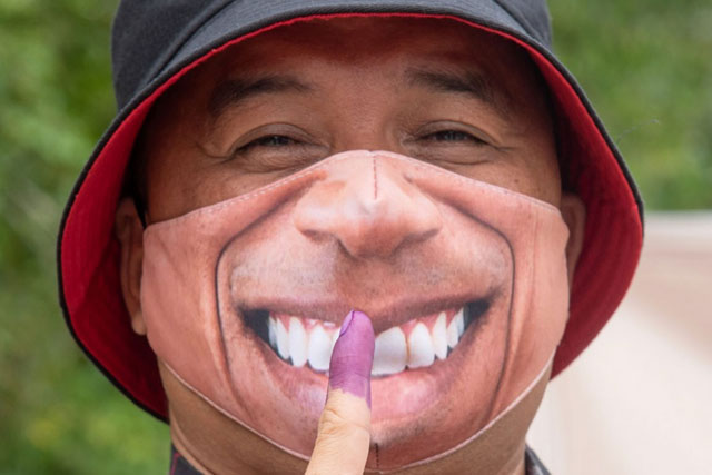 纳闽的一名选民戴上“笑口常开”的口罩，确保脸上一直挂着笑容。