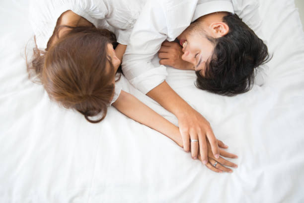 Couple in love holding hands sleep in the bed at home on top view