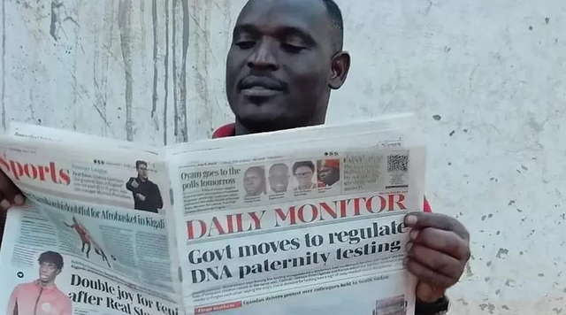 乌干达一男子正在读报纸，头版标题就是“政府采取措施管制亲子鉴定”。