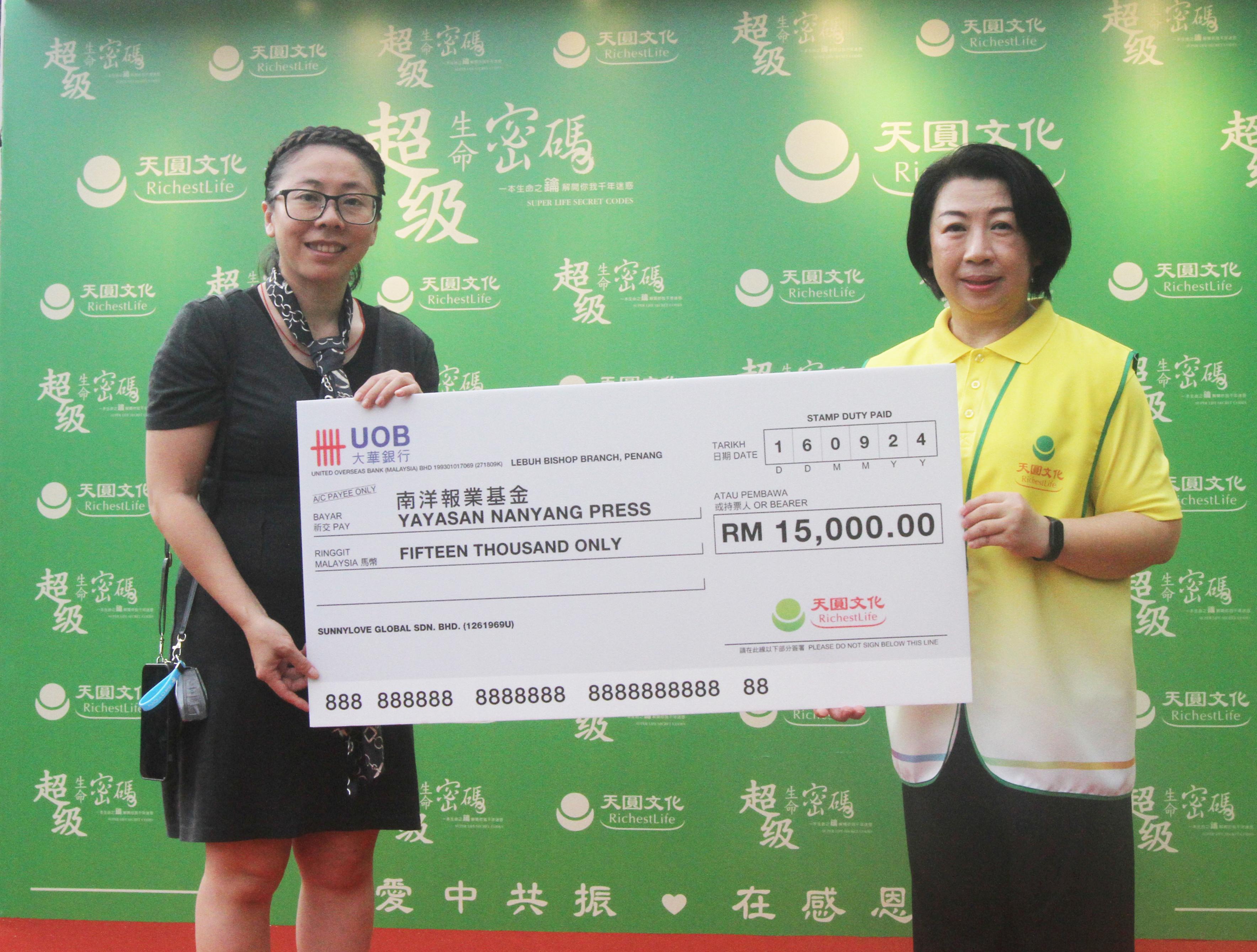 马来西亚天圆文化负责人谢佳均女士(右)移交RM15,000.00模拟支票予南洋报业基金总经理许又尹女士。